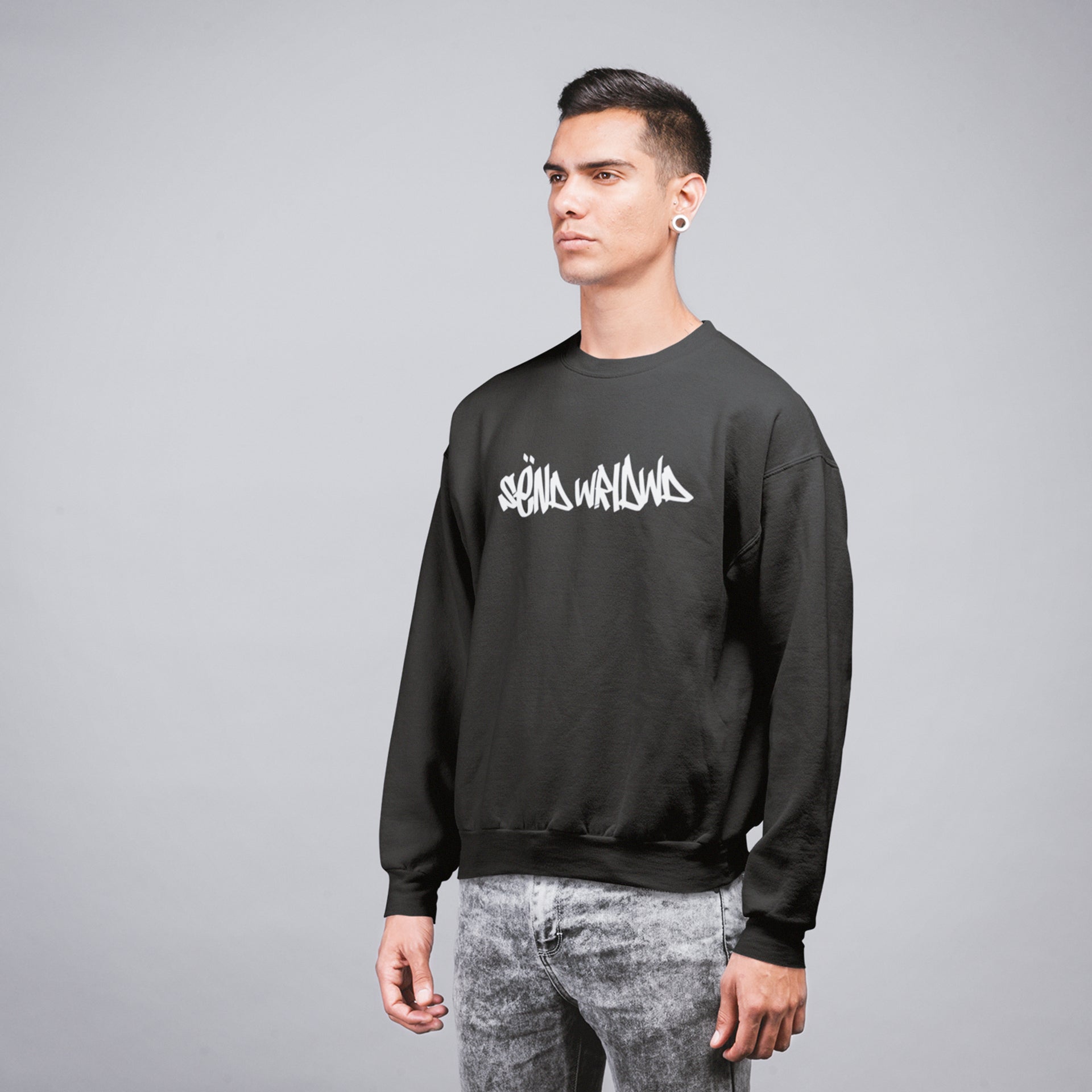 A young motorbike racer wearing a black crewneck sweatshir with a sënd graffiti tag print on the chest
