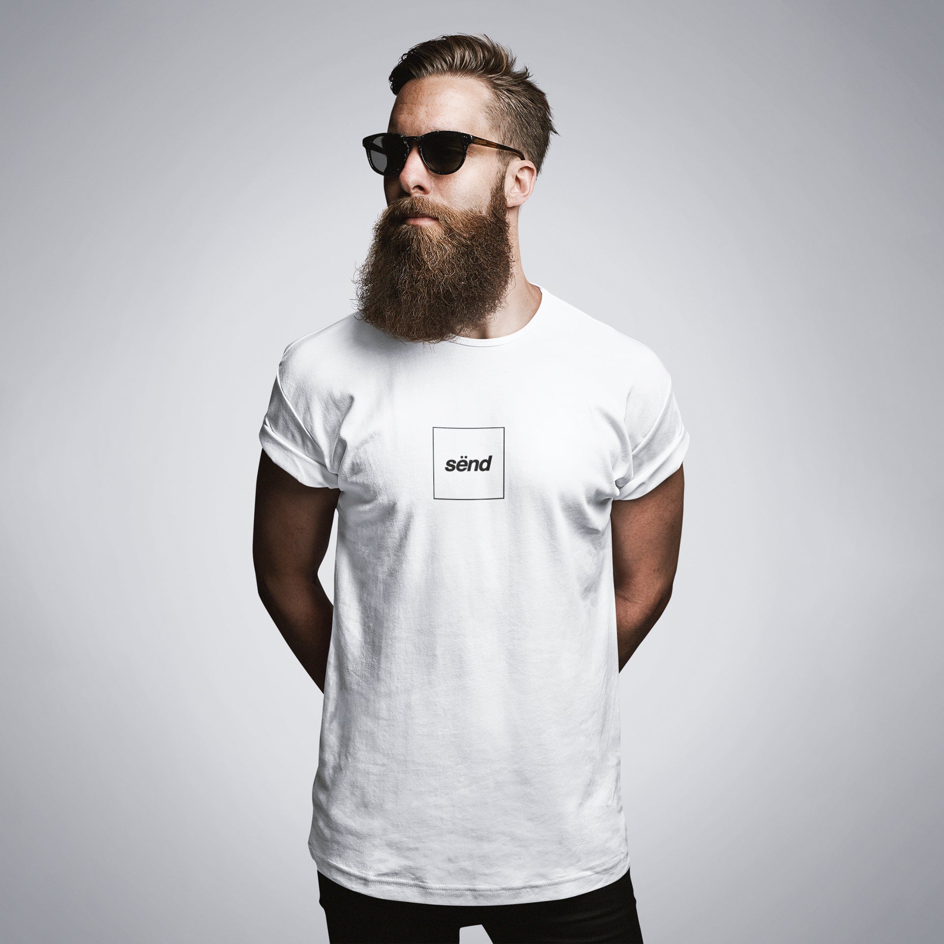 A motorbiker with a beard and sunglasses wearing a white t-shirt with a sënd logo print on the chest