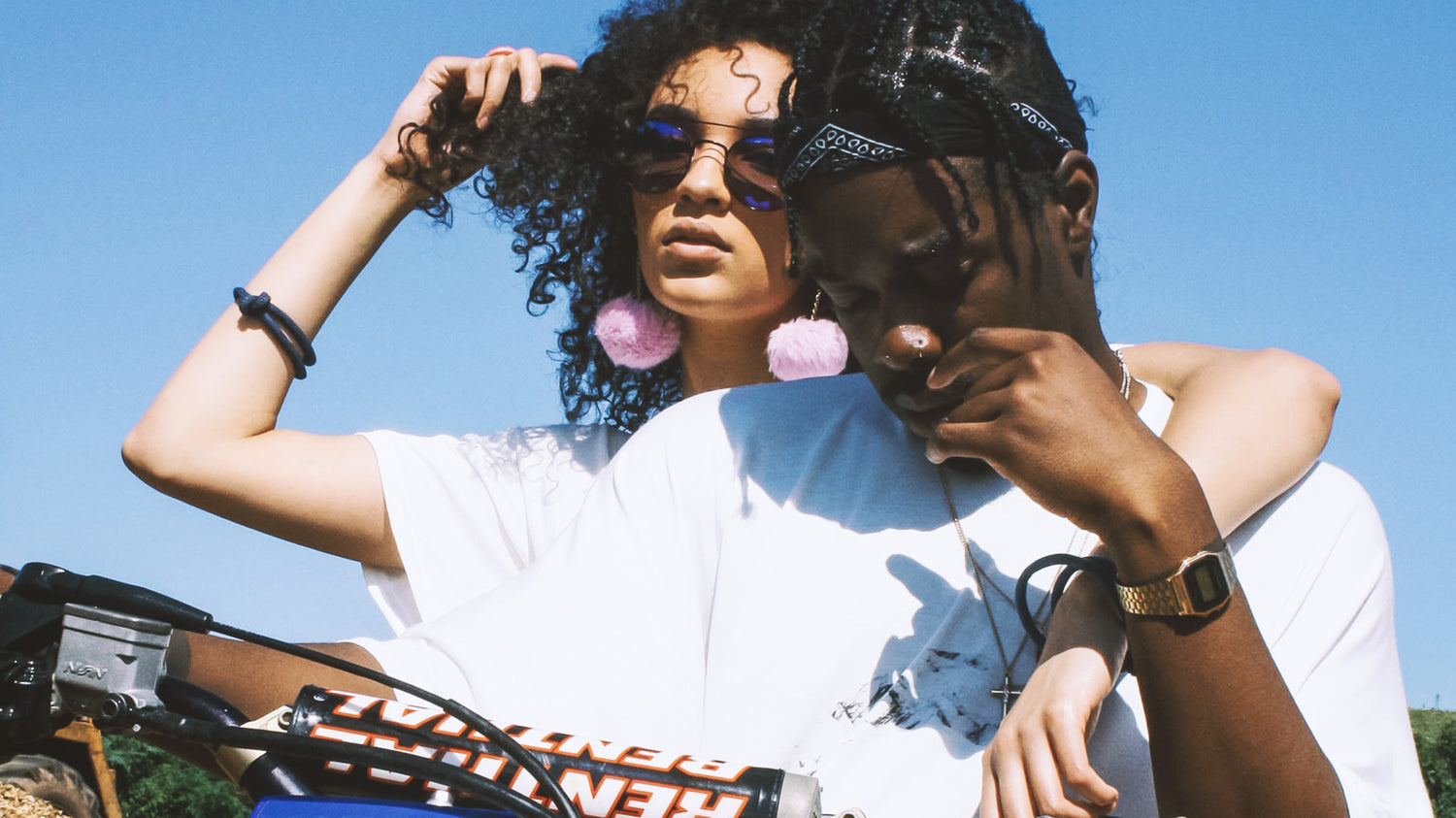 Stylish black couple sitting on an electric dirt bike together, wearing white oversize t-shirts 