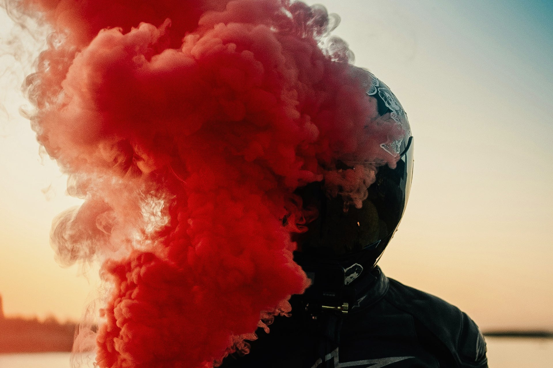 A motorbike streetracer holding a red smoke torch