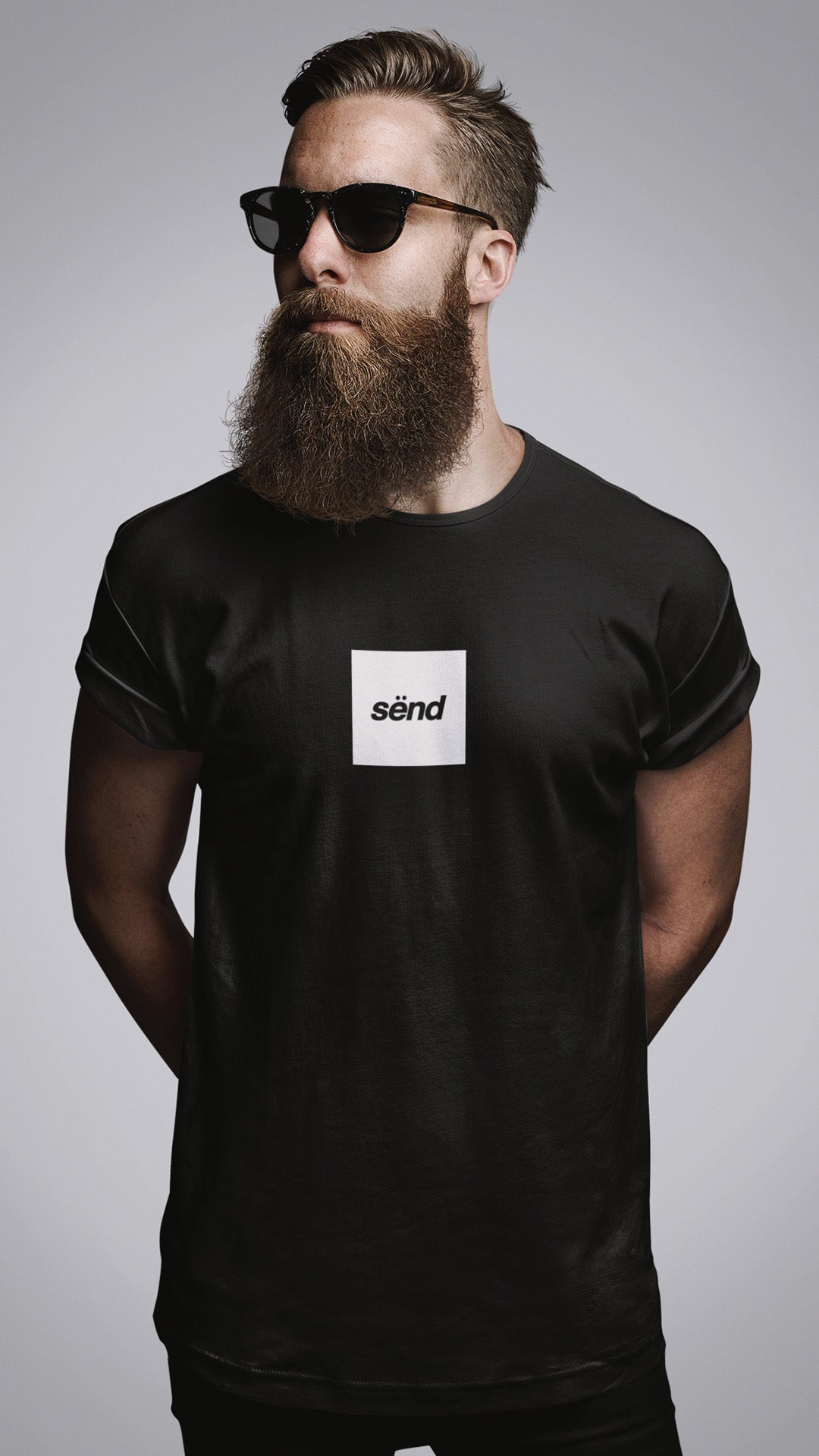 A young motorbike rider with a beard wearing a black t-shirt with a white sënd print on the chest